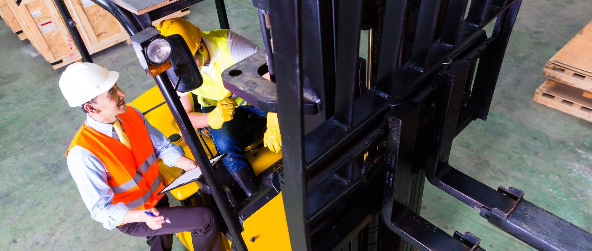 Photo of a man getting some training for driving a forklift truck within a warehouse environment.
