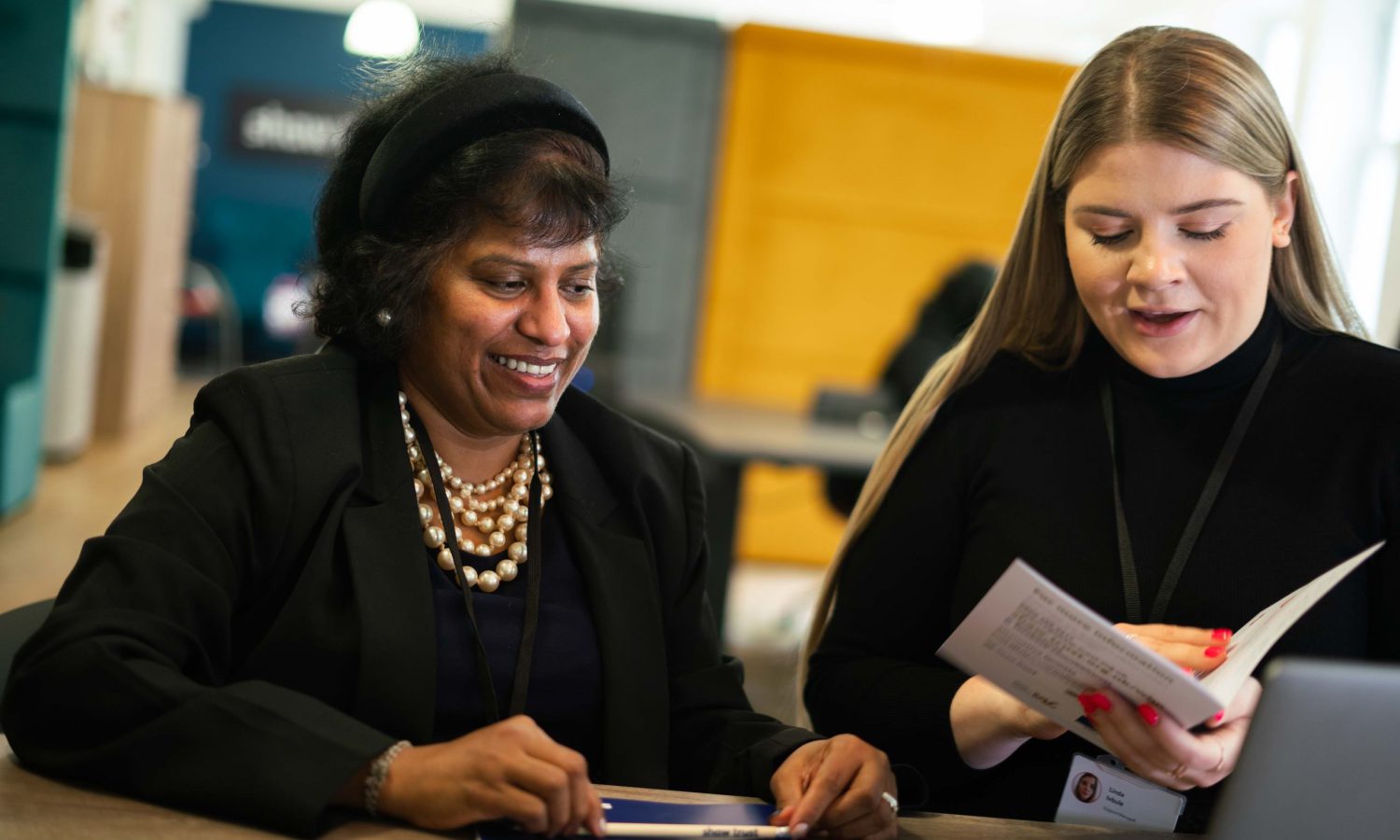Two women sat at a desk looking at a brochure