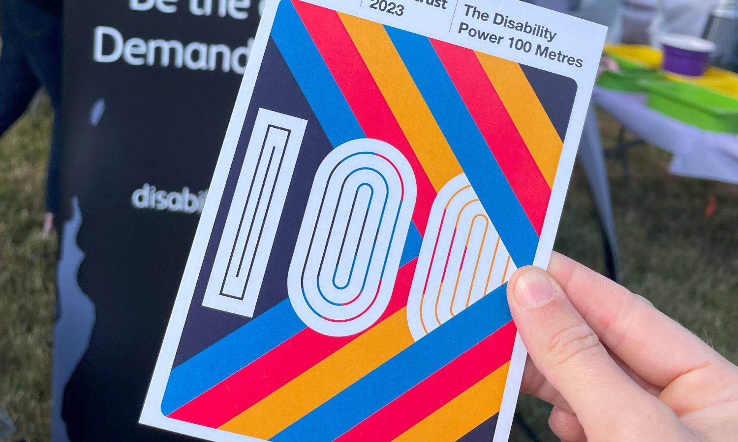 a retro, 70s inspired DP100 postcard with coloured stripes and 100 across the middle.