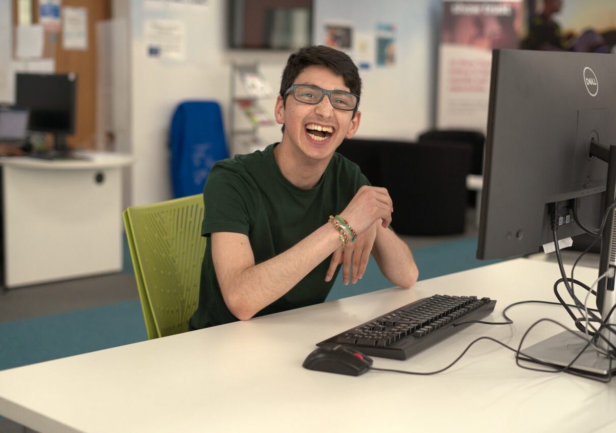 Person smiling sat next to computer