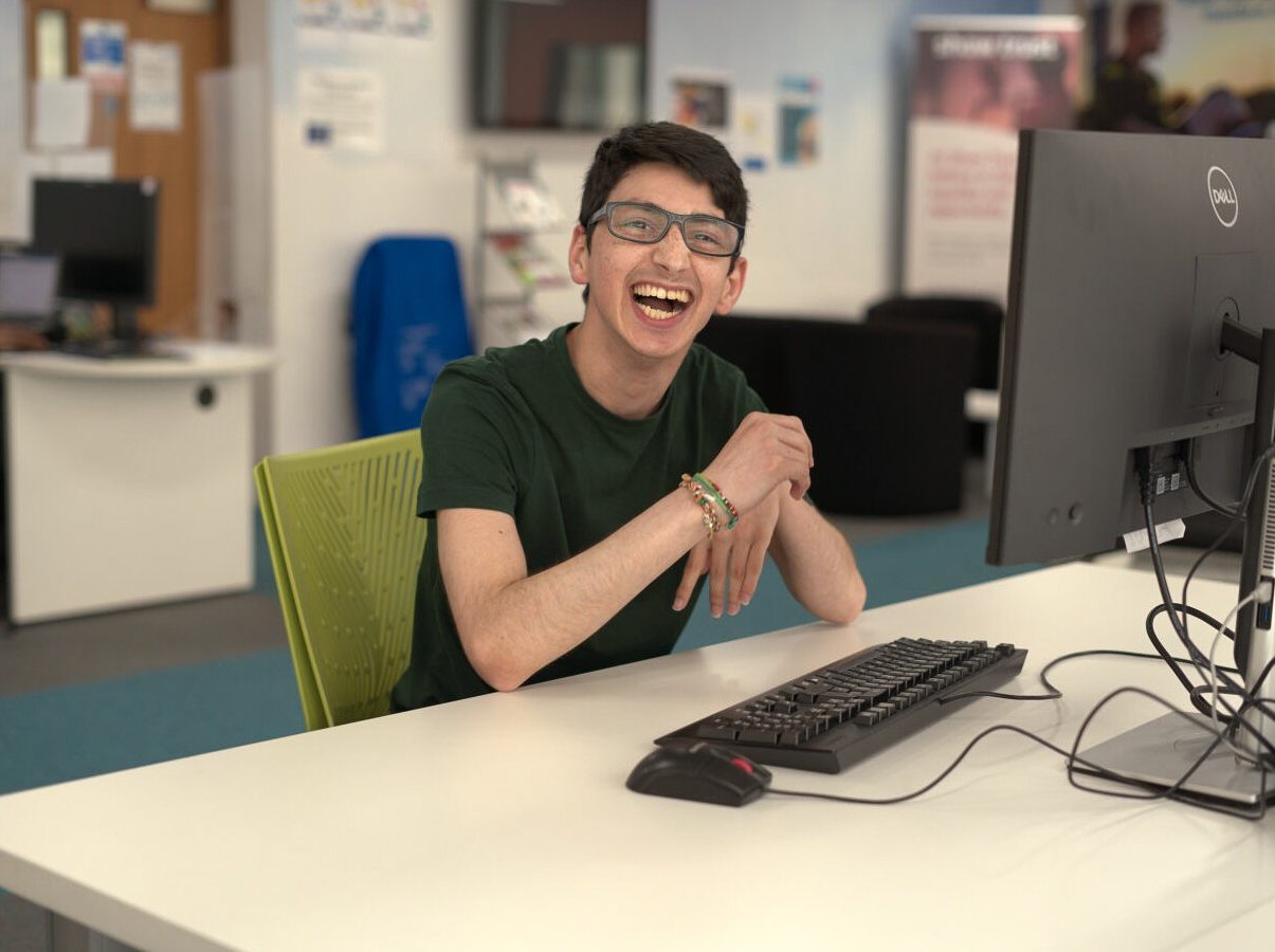 Person smiling sat next to computer